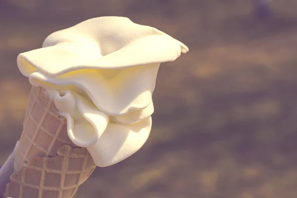 Cono di cialde con gelato cremoso al sole su uno sfondo di erba verde — Foto Stock