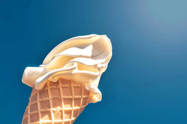 Cono di cialde con gelato cremoso al sole su uno sfondo di cielo blu — Foto Stock