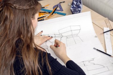 Kadın mimar bir plan çizer, tasarım, geometrik şekiller ofis masasındaki büyük kağıt üzerine kurşun kalemle çizer..