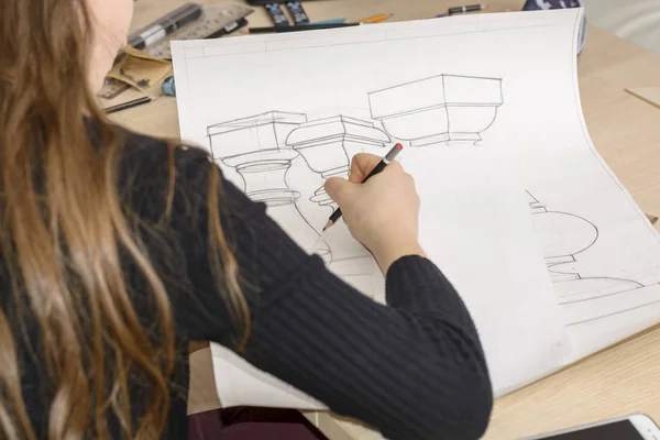 女性建築家はオフィスの机の上に大きな紙の上に鉛筆で計画、デザイン、幾何学的な形を描きます. — ストック写真