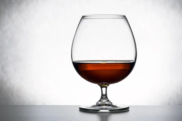 Glas Brandy und Schokostückchen, ein einziges Glas Brandy, halb leer, halb voll. Abstraktion, das Konzept der Einsamkeit, Alkoholismus — Stockfoto