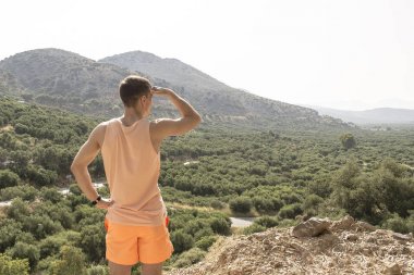 Yalnız genç adam dağda duruyor ve mesafe içine görünüyor. kavram - araştırma, arama, gol, ileriye taşımak, başarı elde.