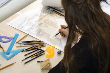 Kadın mimar bir plan çizer, tasarım, geometrik şekiller ofis masasındaki büyük kağıt üzerine kurşun kalemle çizer..