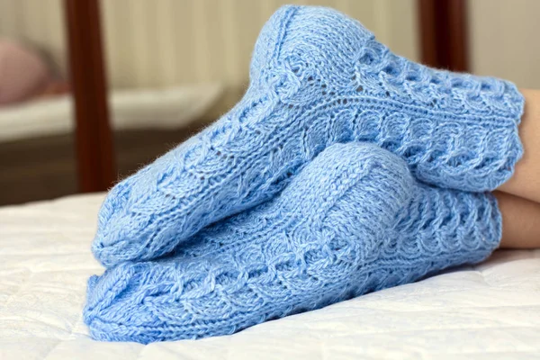 Женские ноги под одеялом на кровати в синих шерстяных носках. холодная погода, отдых, дом отдыха — стоковое фото