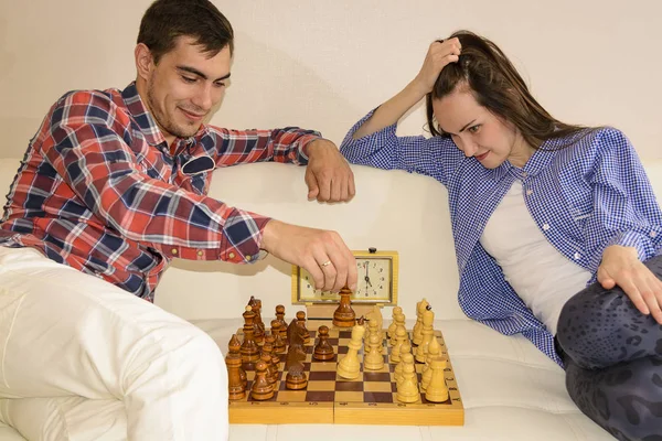 Relaxed young couple playing chess at home lying on sofa. won - Friendship. — Stock Photo, Image