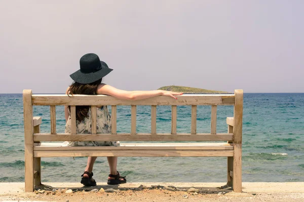 Menina feliz em um chapéu sentado em um fundo do mar azul — Fotografia de Stock