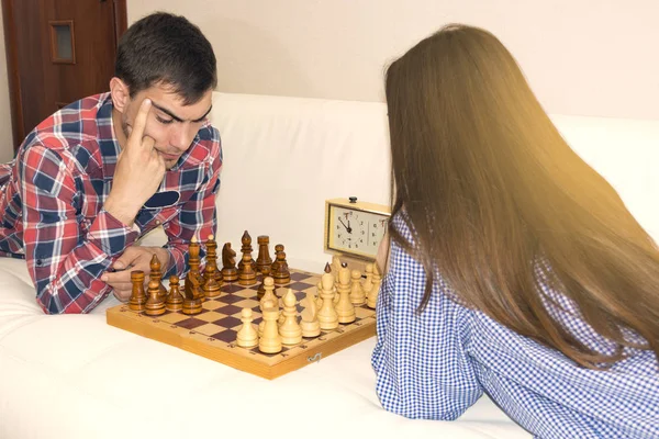 Χαλαρή νεαρό ζευγάρι παίζει σκάκι στο σπίτι ξαπλωμένος στον καναπέ. Won - φιλία. — Φωτογραφία Αρχείου