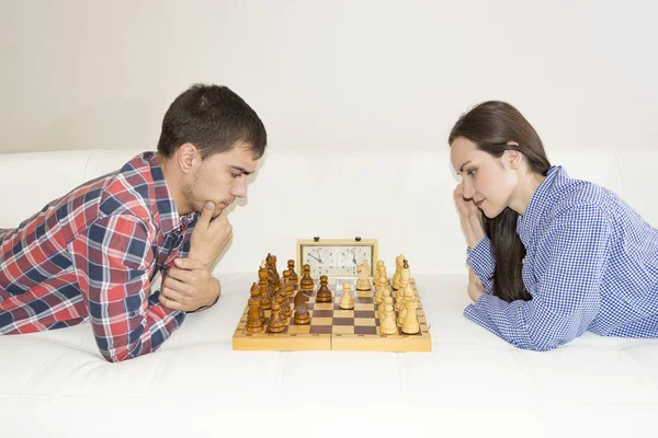 Relaxed young couple playing chess at home lying on sofa. won - Friendship. — Stock Photo, Image