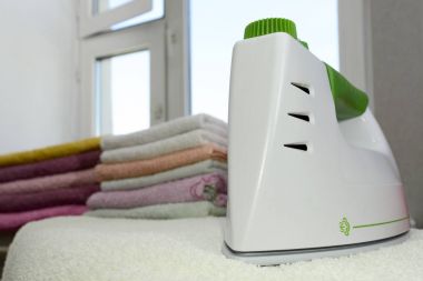 Keten Buhar jeneratörü ile Ütü. Demir yanında yalan ütülenmiş havlu yığını. Küçük delikler ile kaplı Teflon taban levhasını