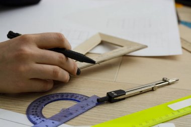 Mimar bir plan, grafik, tasarım, geometrik şekiller genç kadın - büyük Ofis Masası, kağıt üzerine kalem tarafından çizer. görüntüyü Kırp