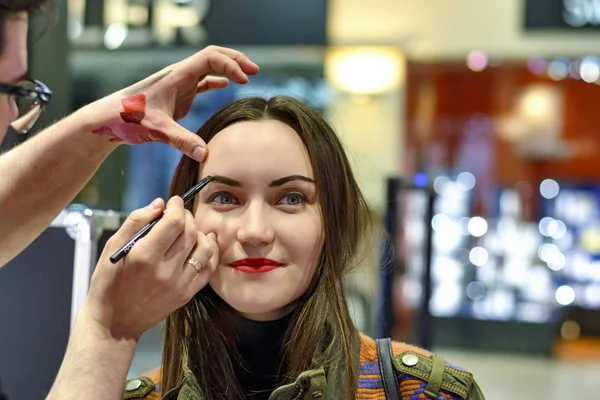 Schöne Brünette mit rotem Lippenstift testet die Lidschatten im Beauty Store — Stockfoto