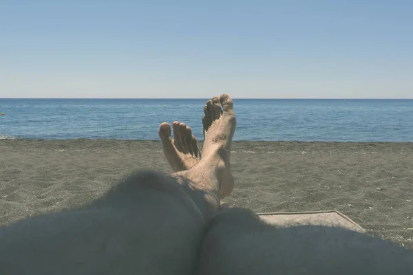 Masculino piernas peludas bronceado en el sol con vistas al mar. el concepto de relajación, ocio, viajes — Foto de Stock