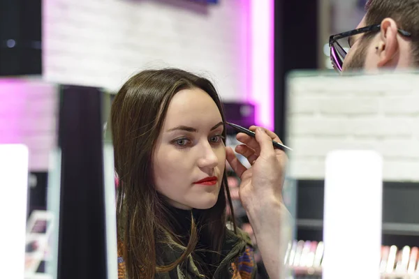 Mooie brunette met rode lippenstift is het testen van de eyeshadows in schoonheid winkel — Stockfoto