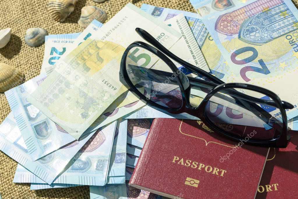 Adventure concept. Traveler items on white table. Glasses, passport, euros, Notepad with pen and shell.