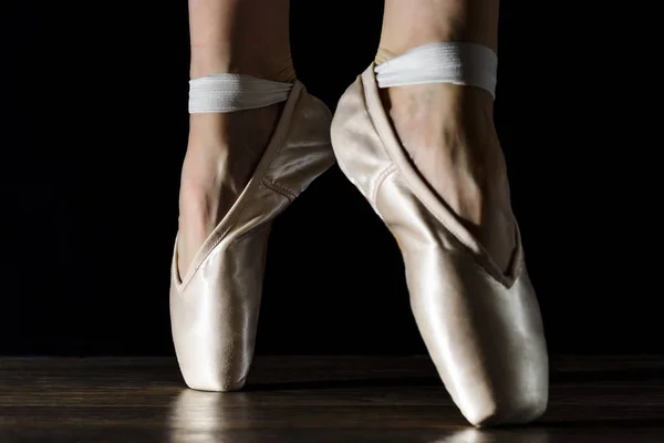Close-up classic ballerina's legs in pointes on the black wooden floor — Stock Photo, Image