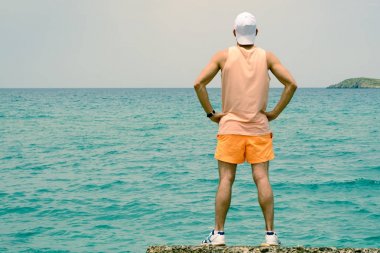 Genç bir adam iskele üzerinde sırtında, mesafe içine görünüyor