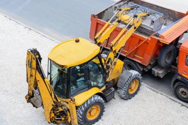 Sarı traktör çakıl turuncu bir kamyona yükleniyor. Teknoloji yol çalışmaları yol açar. çevre düzenlemesi
