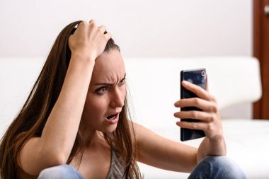 Onun baş ve Smartphone-e doğru görünüyor tutan genç kadın. Ne gördüğünü tarafından sıkıntılı