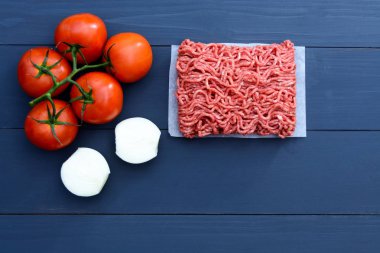 Dal kırmızı domates ve kopya alanı gri bir ahşap zemin üzerine dilimlenmiş soğan kıyılmış et