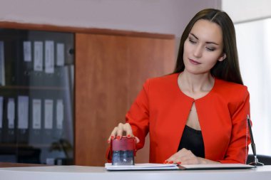 Parlak kırmızı iş takım elbiseli bir kadın patron bir mühür sözleşmesine Resepsiyon ofiste koyar.