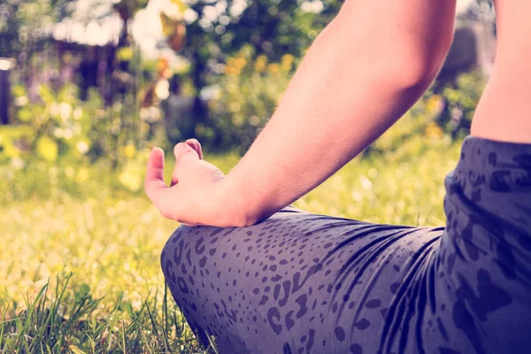 Primer plano de la mujer meditando sobre la hierba verde en el sol — Foto de Stock