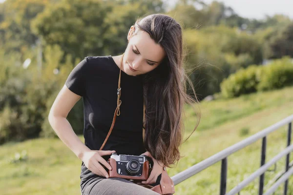 Giovane felice fotografo femminile cammina nel parco con fotocamera retrò — Foto Stock