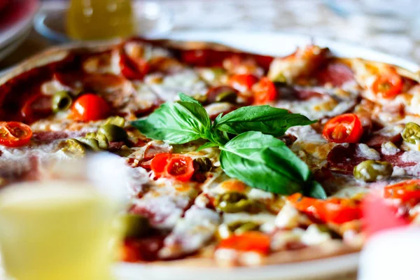 A tasty pizza with vegetables, meat, and sauces on a cafe on a white plate. Close up. Royalty Free Stock Photos