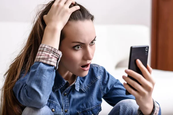 Onun baş ve Smartphone-e doğru görünüyor tutan genç kadın. Ne gördüğünü tarafından sıkıntılı