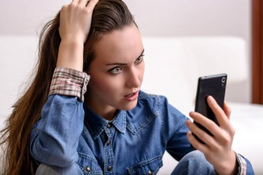 Onun baş ve Smartphone-e doğru görünüyor tutan genç kadın. Ne gördüğünü tarafından sıkıntılı