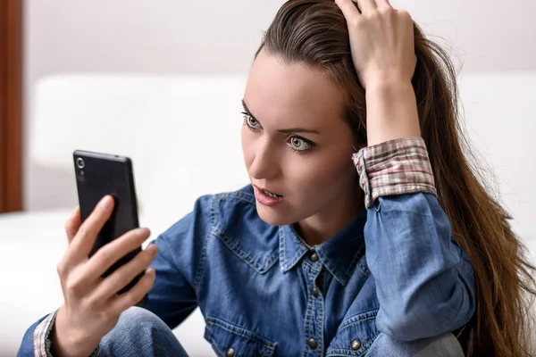 Onun baş ve Smartphone-e doğru görünüyor tutan genç kadın. Ne gördüğünü tarafından sıkıntılı