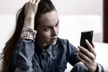 Onun baş ve Smartphone-e doğru görünüyor tutan genç kadın. Ne gördüğünü tarafından sıkıntılı