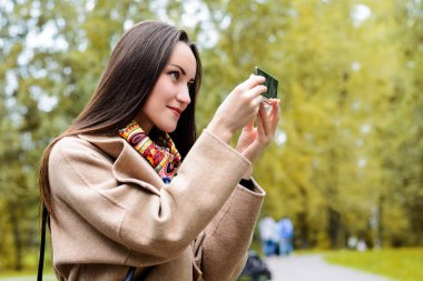 Genç kız onun makyaj sonbahar Park bir bankta oturan sabitleme