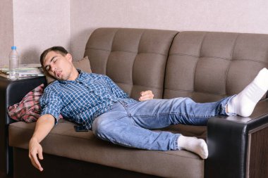 Odasında, sonra iş, bir partiden sonra sarhoş yorgun kanepede uyuyan genç adam. Zaten uykuya düştü.