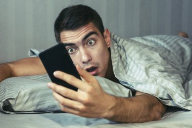 Genç sinirli ve gergin adam geç. O, smartphone vasıl seyir uyanma ve şok olduğunu. Hayatın, uykusuzluk modern bir ritmi kavramı