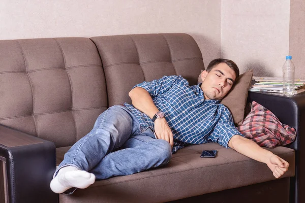 Un joven se quedó dormido en el sofá mientras miraba la televisión . — Foto de Stock
