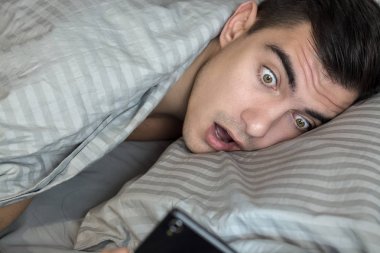Genç sinirli ve gergin adam geç. O, smartphone vasıl seyir uyanma ve şok olduğunu. Hayatın, uykusuzluk modern bir ritmi kavramı
