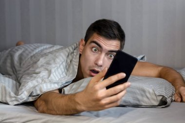 Genç sinirli ve gergin adam geç. O, smartphone vasıl seyir uyanma ve şok olduğunu. Hayatın, uykusuzluk modern bir ritmi kavramı