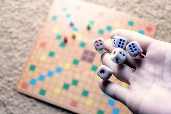 Hand werfen weiße Würfel Hintergrund bunte verschwommene Brettspiel. der dynamische Moment des Spiels, selektiver Fokus. — Stockfoto