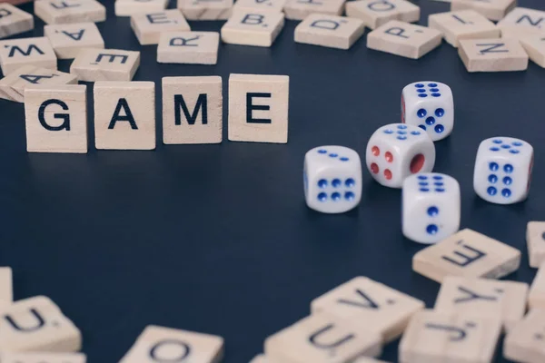 Word GAME with wooden letters on black Board with dice and letter in the circle — Stock Photo, Image