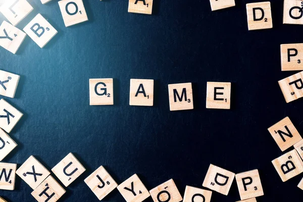 Word GAME cu litere din lemn pe tablă neagră cu zaruri și litere în cerc — Fotografie, imagine de stoc
