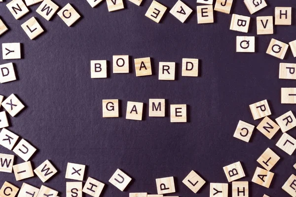 Word GAME with wooden letters on black Board with dice and letter in the circle