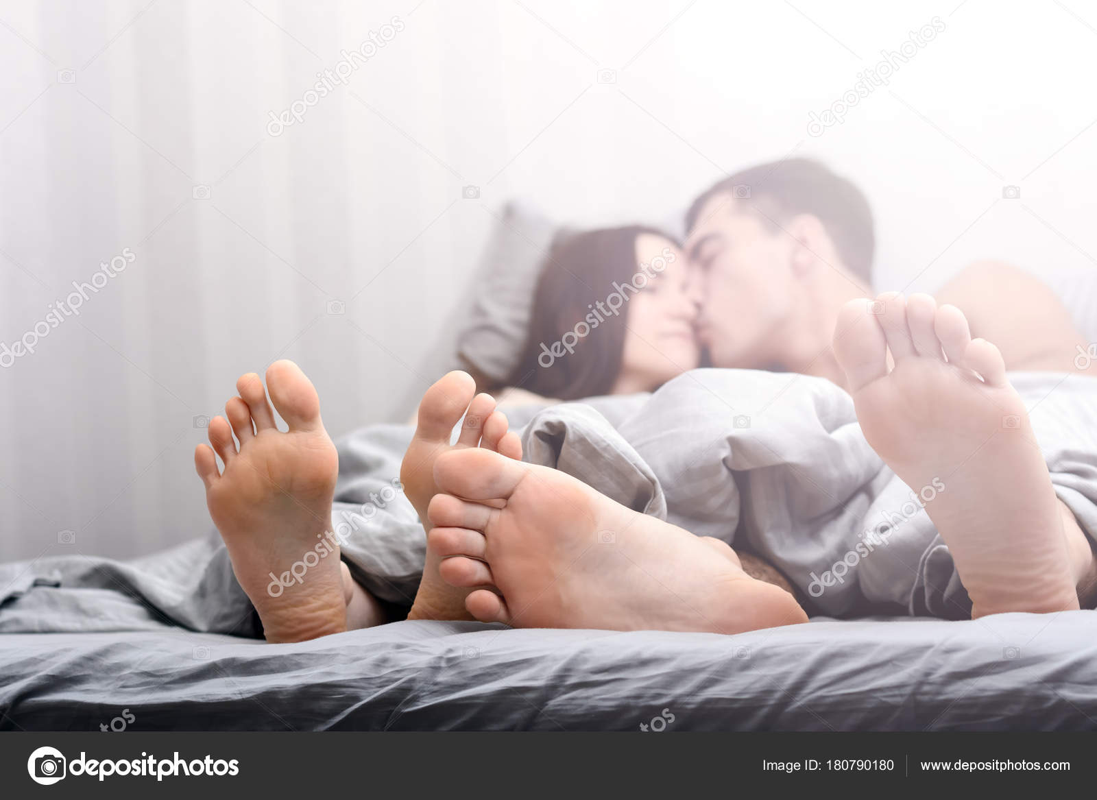 夫妻在床上玩得很开心。裸脚爱好者伸出毯子下. ——图库图片© RasselBor 180790180