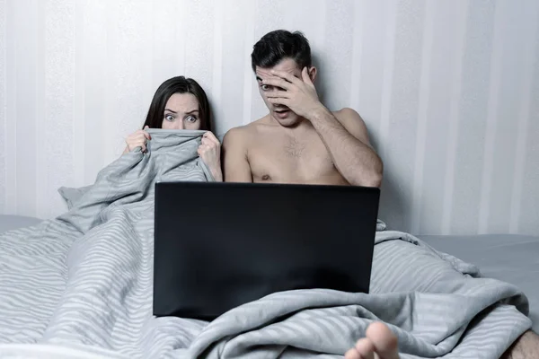 Giovane coppia di famiglia utilizzando il computer portatile e guardando film a letto. film horror — Foto Stock