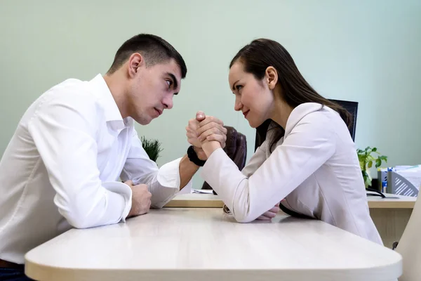 Man and woman in office clothes wrestling on hand at the Desk in the office — Stock Photo, Image