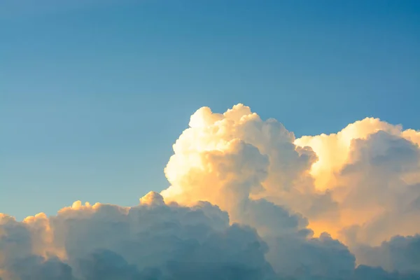 Vita fluffiga moln i klarblå himmel i en ljust orange solnedgång — Stockfoto