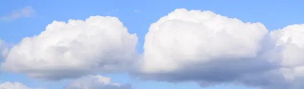 Weiße flauschige Wolken am klaren blauen Himmel — Stockfoto