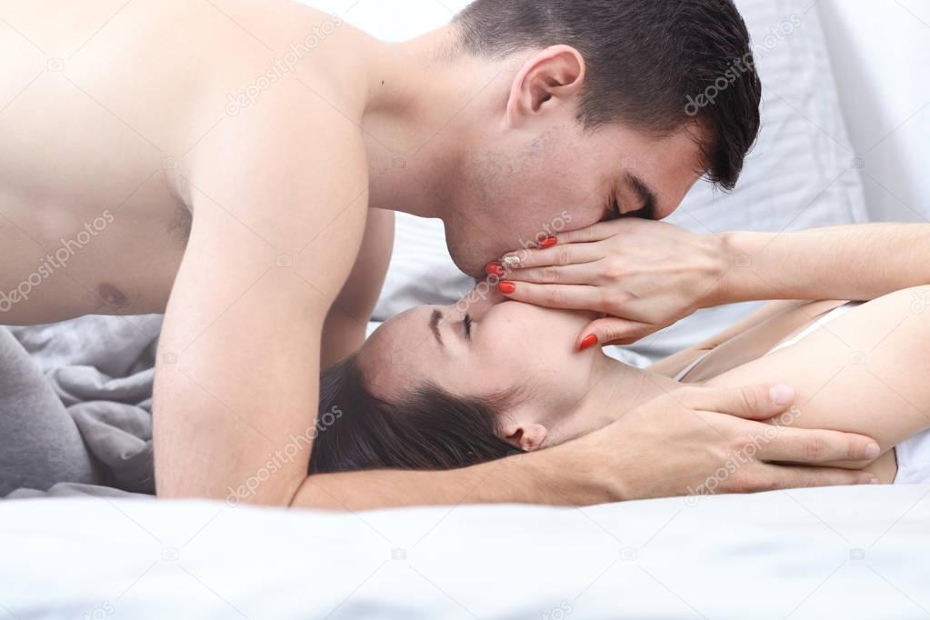 Newlyweds gently kissing in bed in the early morning, good morning.