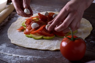 ön sebze bisküvi, pişirme süreci görünümünü pizza. kadınların elleri mozzarella peynirli domates ve kabak rulo bir hamur üzerinde düzenleme