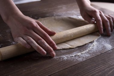 Bir oklava ile el hamur rulo bir kahverengi ahşap masa, yan ışık, önden görünüm