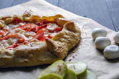 Ev yapımı pizza domates, mozzarella peyniri ve ahşap bir masa üzerinde kabak ile.